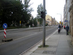 The tram line is in the middle of the street here, but a raised platform is still provided for step-free entry and exit. The signal in the foreground stops traffic to allow boarding and alighting. This side is for trams to Messe, Gleisschleife