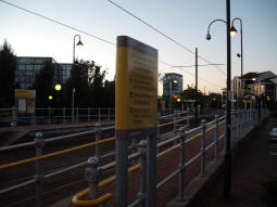 Looking at the station with the sign at the entrance to the platform for trams to Manchester in the foreground