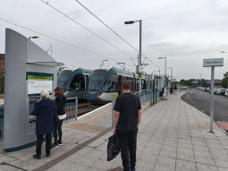 Trams stand at both platforms with the car park to the right